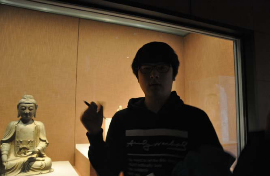 Student Lee Jae-seong enthusiastically explaining in front of a Buddhist statue